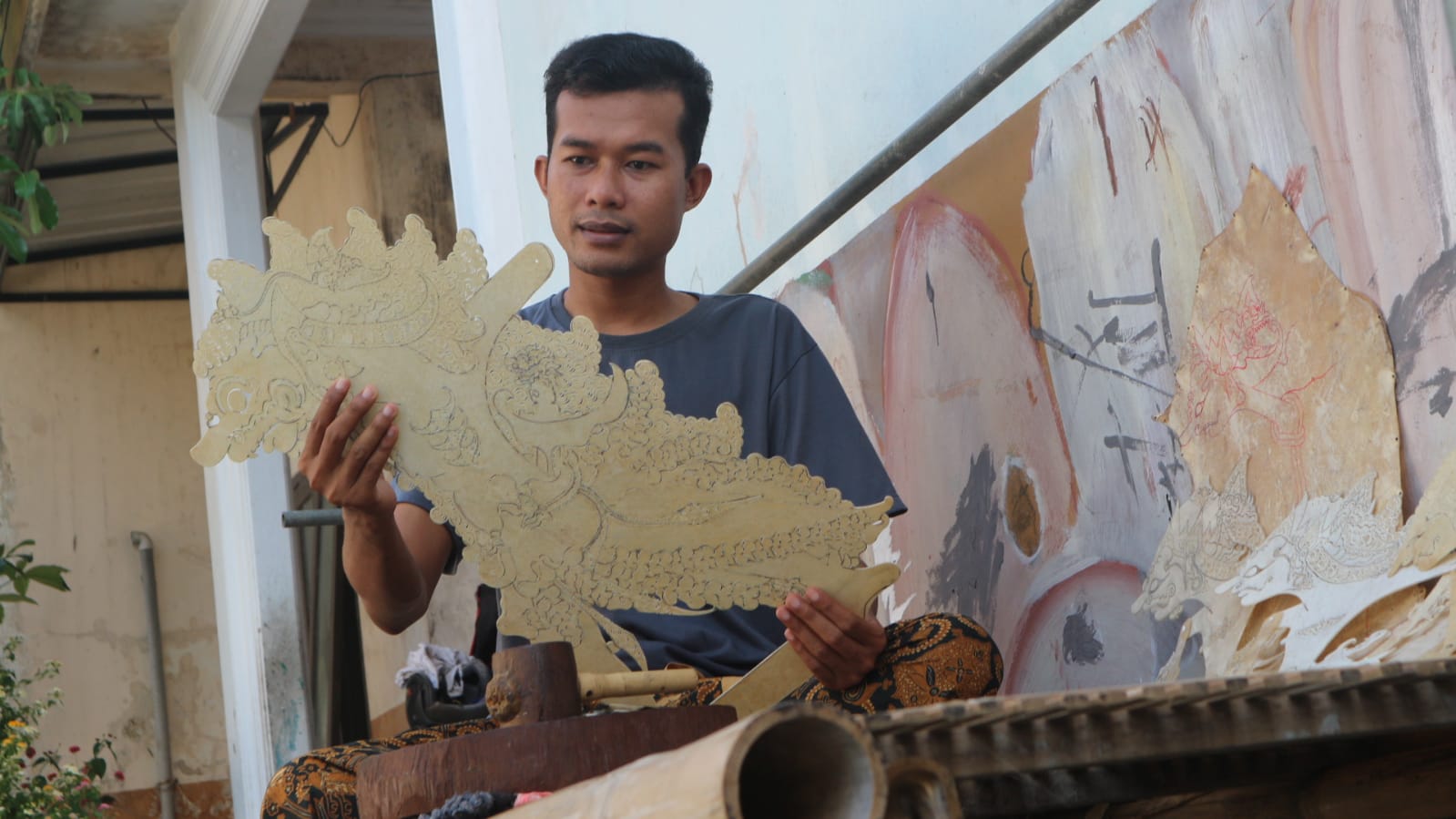 Mengulik Pahatan Wayang Kulit Pemuda Trenggalek 2 Anom mengangkat wayang yang sedang ia pahat