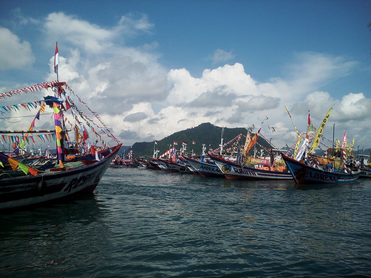 Meriahnya Labuh Laut Larung Sembonyo di Pantai Prigi Trenggalek 3 Deretan kapal nelayan mengiringi tumpeng agung dan sesaji