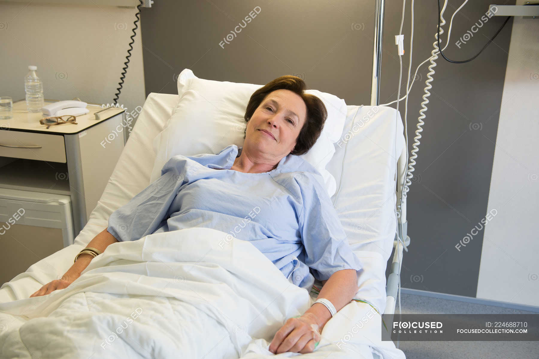 Smiling mature woman lying in hospital bed and looking at camera