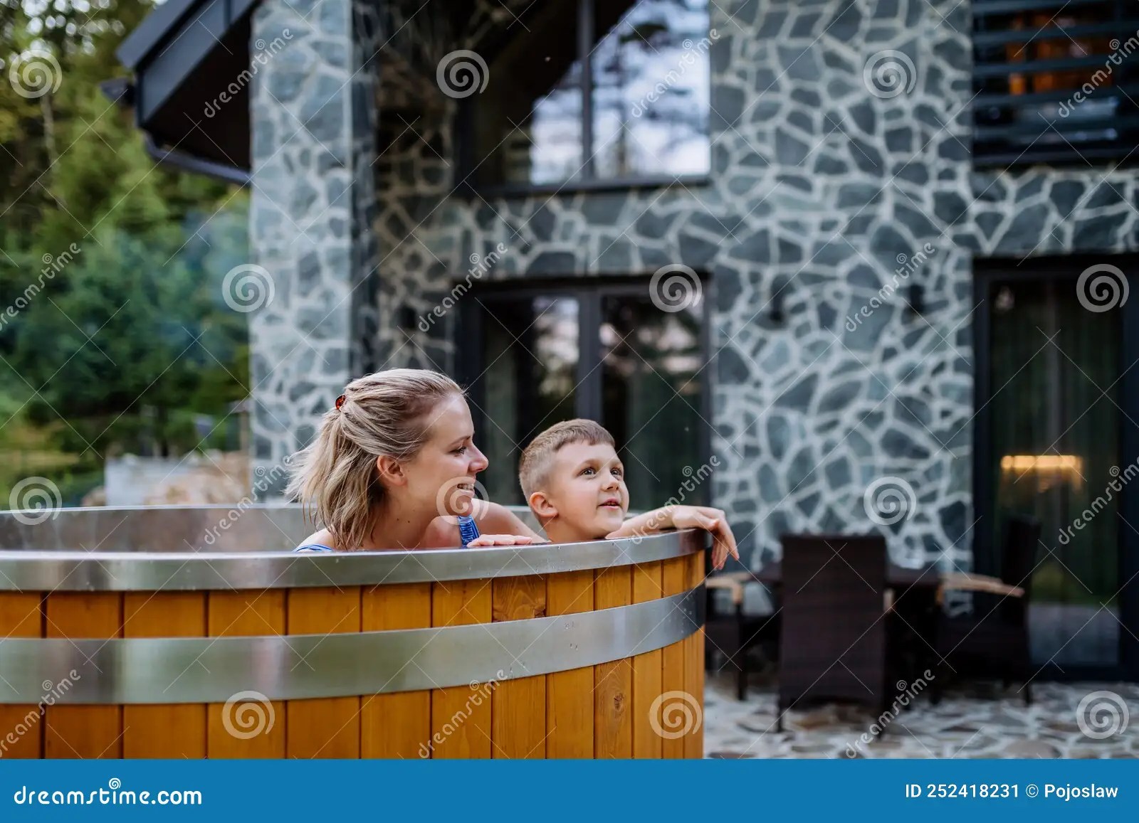 Mother with Her Little Son Enjoying Bathing in Wooden Barrel Hot Tub in