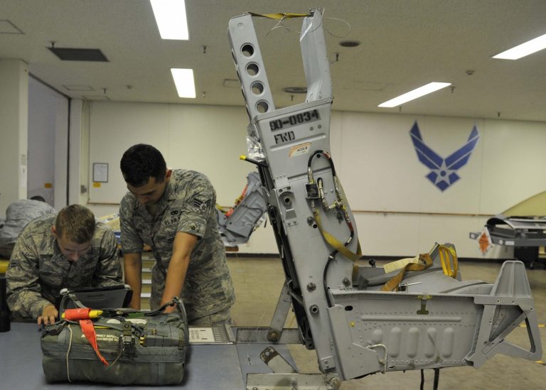 El Soldado Peter Curry y el Cabo Jeffrey Bowen, aprendiz y técnico, respectivamente, de sistemas de escape de tripulaciones del 35º Escuadrón de Mantenimiento del Ejército del Aire estadounidense, consultan una instrucción técnica sobre la instalación de un kit de supervivencia de tripulaciones en la Base Aérea de Misawa, en Japón, el 31 de julio de 2014. Una vez que el equipo de escape recibe el kit de supervivencia de manos de la Sección de Equipo de Vuelo de Tripulaciones, lo instalan en el asiento eyectable de un F16 Fighting Falcon (Foto del Ejército del Aire estadounidense/Soldado Patrick S. Ciccarone).