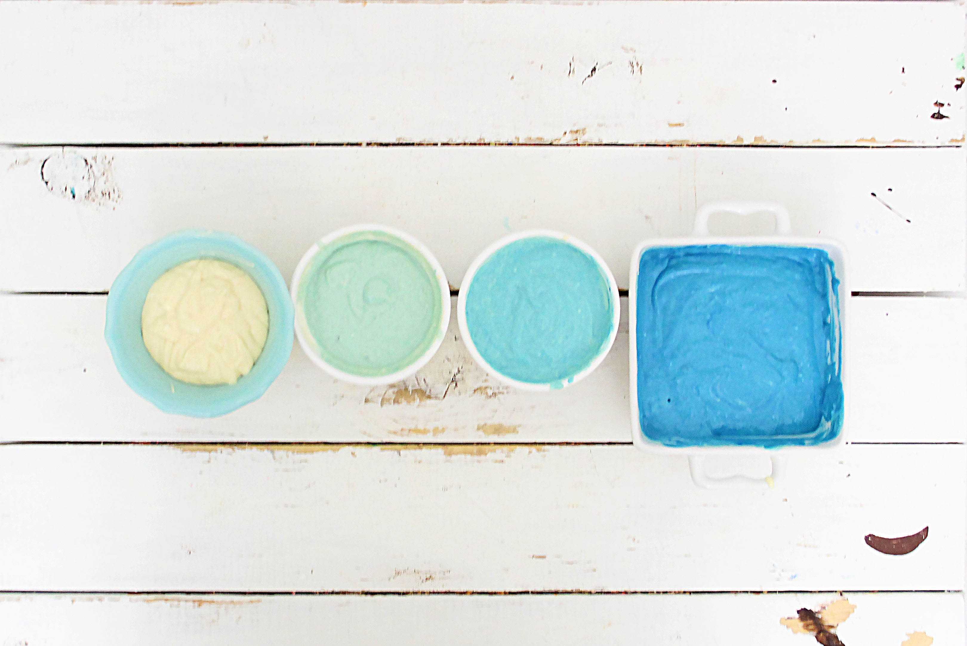 Pancake batter in 4 different bowls with different shades of blue.