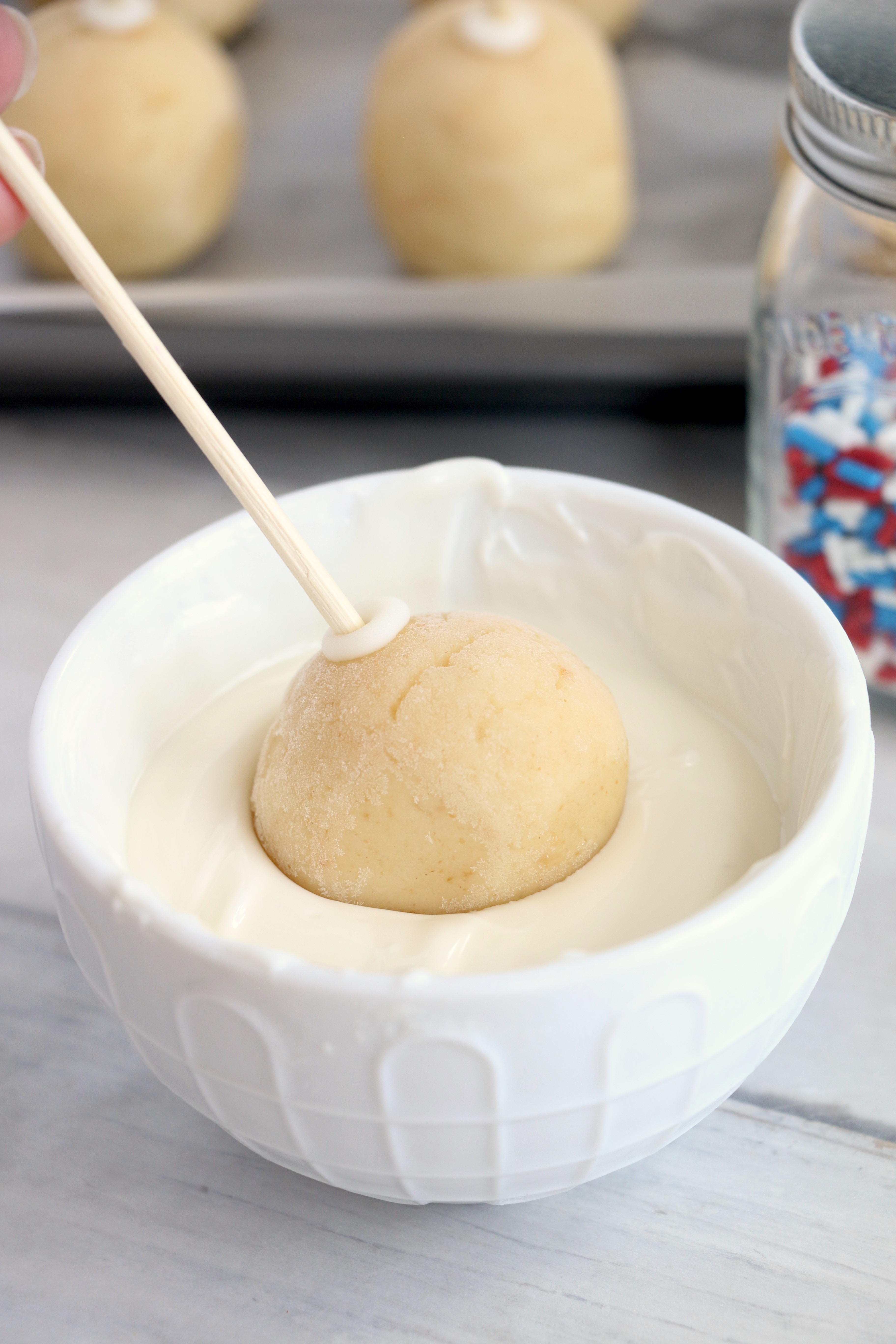 Dipping cake balls into melted white chocolate
