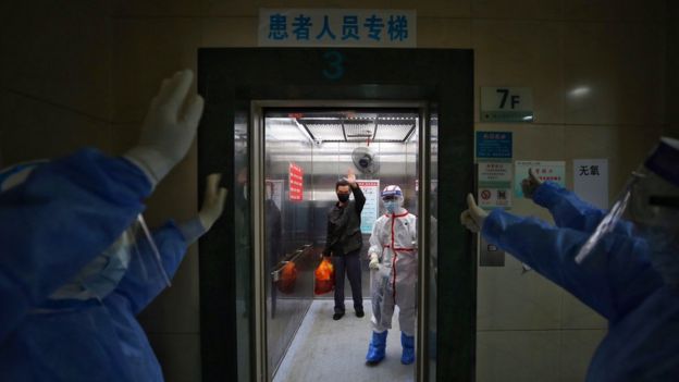 Equipe de hospital em Wuhan, na China, se despede de paciente curado da covid-19, que retribui acenos de dentro de elevador