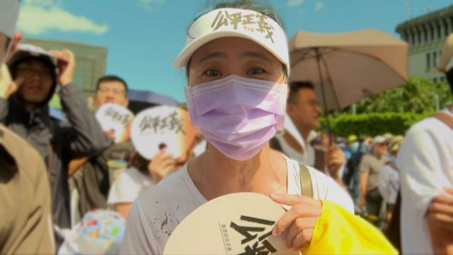 A Taiwanese woman with a mask on among a crowd during a protest