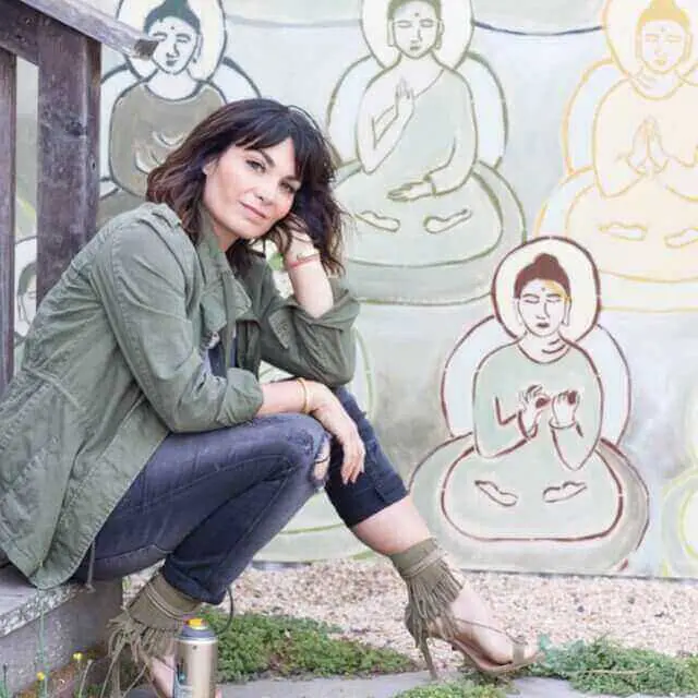 Amanda Giacomini sitting near a wall with Buddha paintings