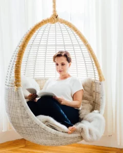 Andrea Ferretti curled up in a basket chair with a book