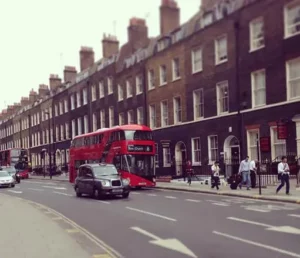 A photo of London streets with red buses, cars and people