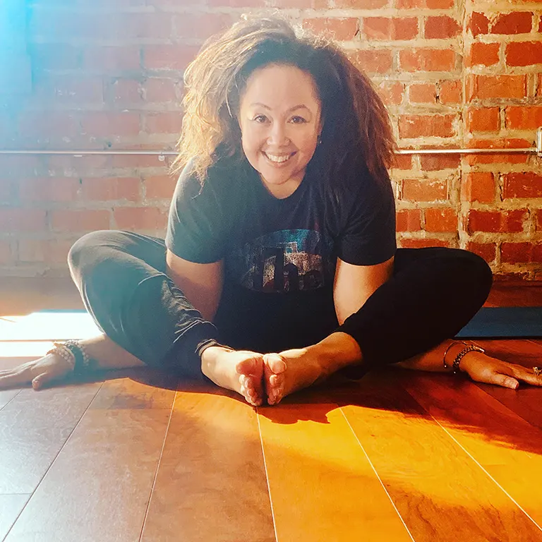 Kristin Booker in a yoga pose, smiling at the camera