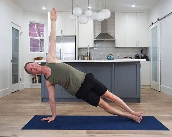Jason Crandell in Side Plank, with the bottom arm stacked, with top arm reaching for the ceiling