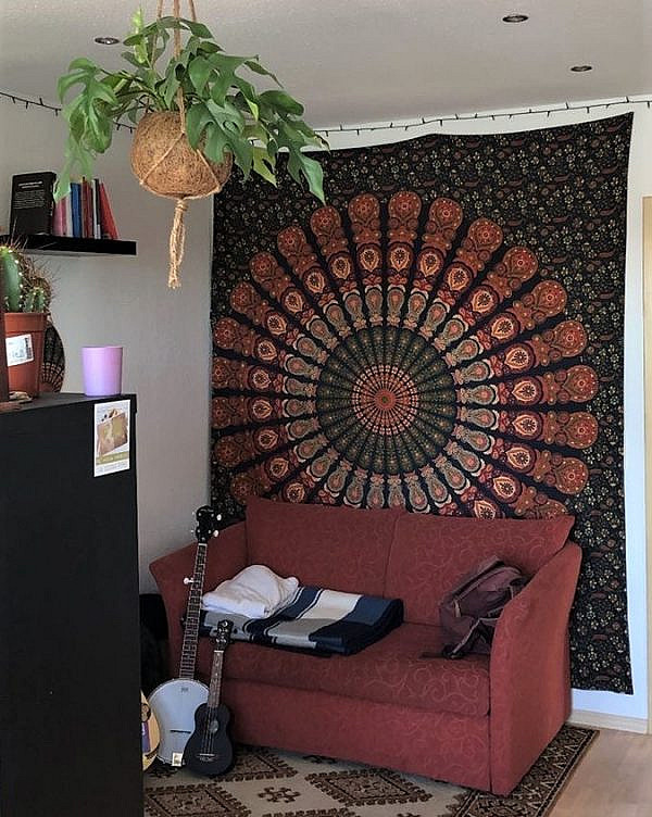 Pfauenfeder Mandala in grün orange als Wandbehang im Wohnzimmer