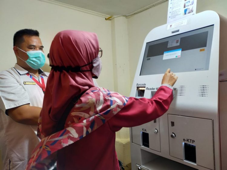 Salah seorang warga sedang menggunakan mesin Anjungan Dukcapil Mandiri (ADM) milik Disdukcapil Kota Padang. (foto: Diskominfo Kota Padang)