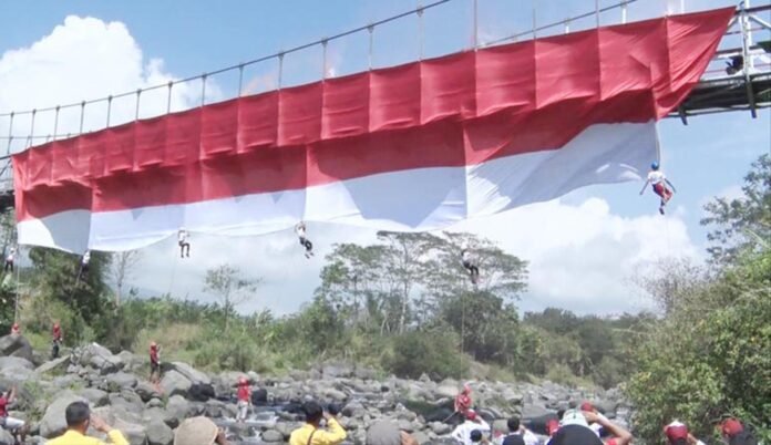 KIBARKAN. Enam pemanjat tebing cilik mengibarkan bendera raksasa di Jembatan Sekrikil Parakan Temanggung Rabu kemarin. (Foto:Setyo wuwuh/temanggung ekspres)