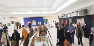 PAMERAN. Sejumlah pengunjung saat menikmati karya lukisan yang dipamerkan di auditorium SMK Bharasa. (Foto lukman)