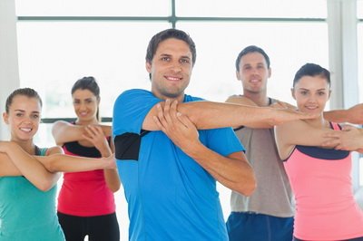 Portrait of sporty people stretching hands at yoga class in fitness studio