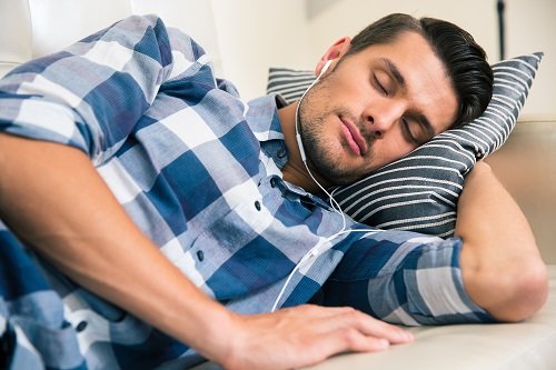 Man sleeping on the sofa with headphones at home