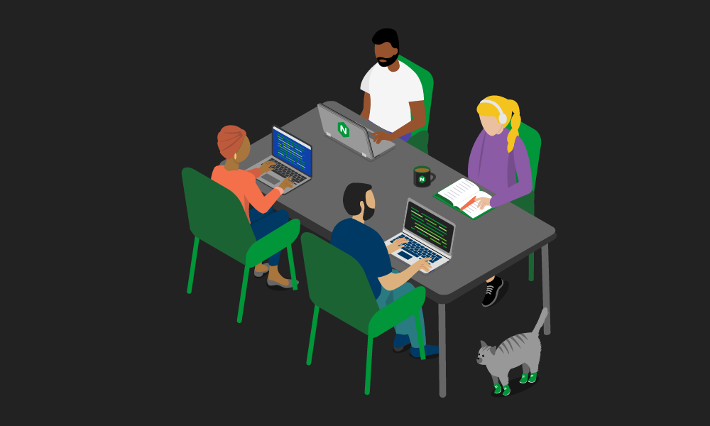 Four people sitting and working at a table with laptops and a notebook