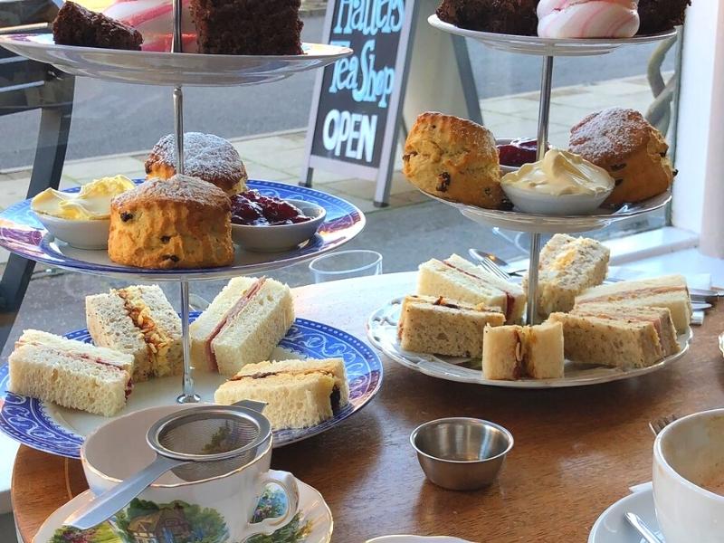 Two cake stands with small sandwiches, scones with clotted cream and jam