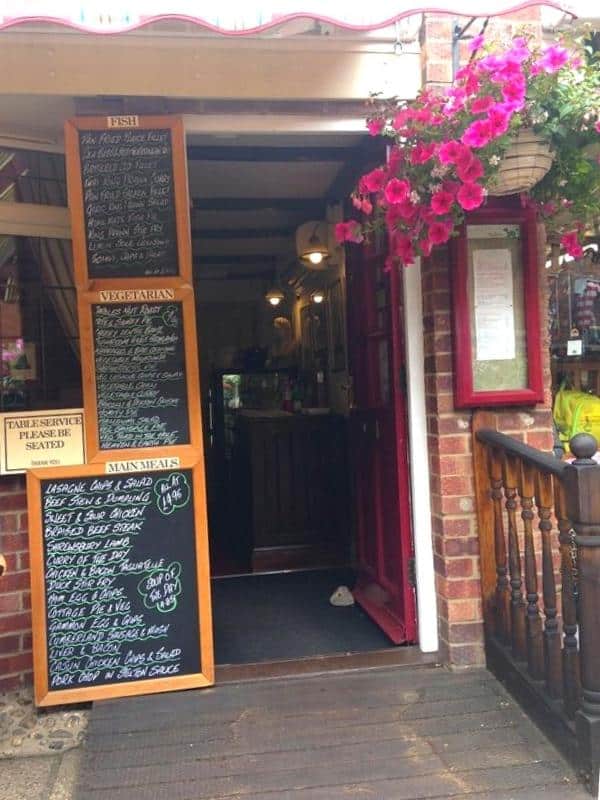 chalk menu boards by a red painted entrance door to a Sheringham tearoom