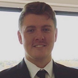 a man wearing a suit and tie smiling at the camera