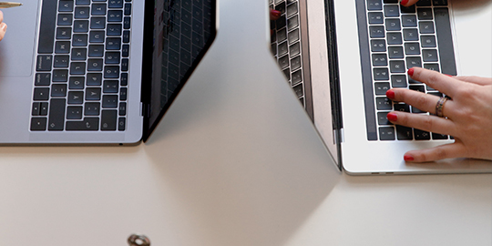 a person using a laptop computer sitting on top of a desk