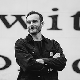 Alumni posing in front of screen with his arms crossed