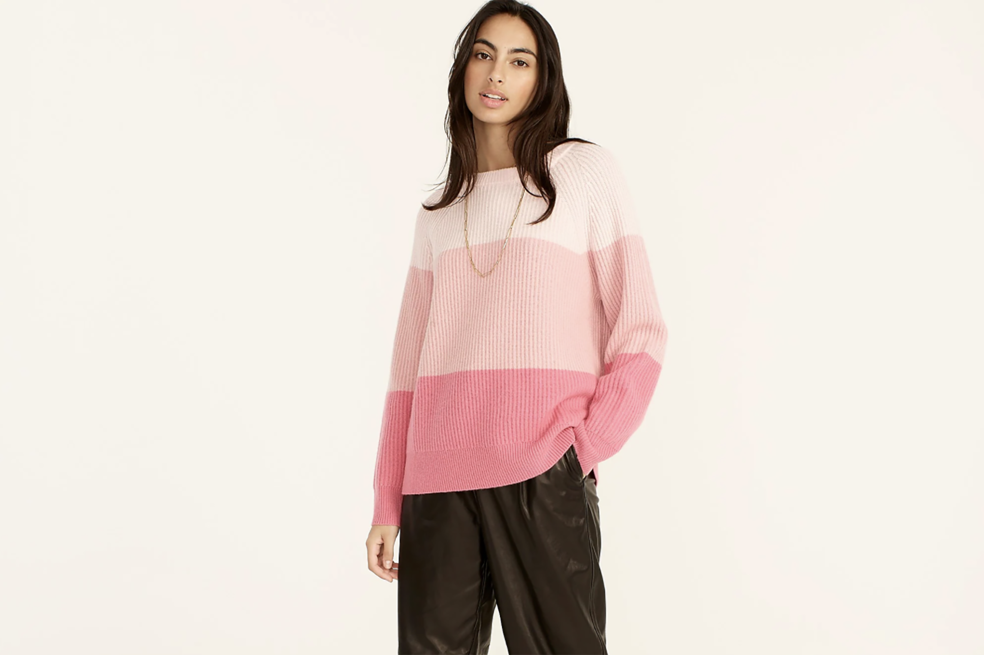 A woman in a pink striped sweater and black pants 