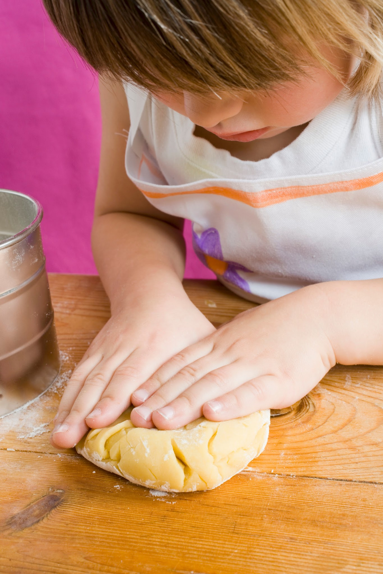 child's hands pressing out dough on a table - one of 75 calm down tools for kids