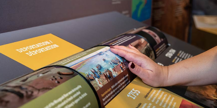 A visitor's hand interacts with an exhibit spinner that has text on it.