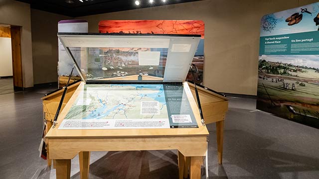 A large table with a map and overlays in an exhbit room.