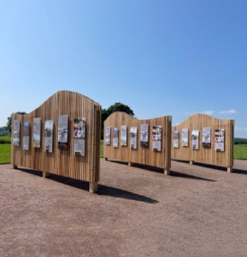 Three wooden walls outdoors with interpretive panels.