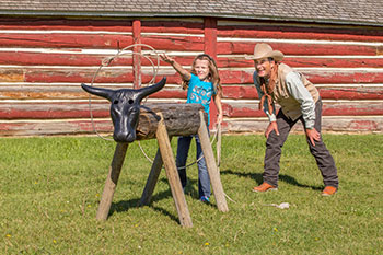 A young visitor tries her hand at roping while watched by an interpreter