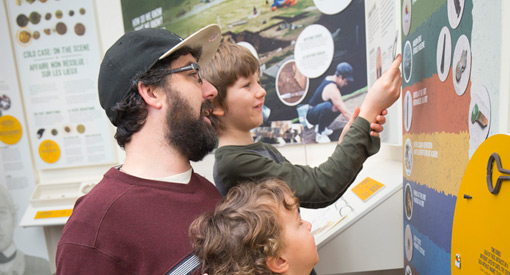 Une famille regarde un panneau d’exposition sur le mur.