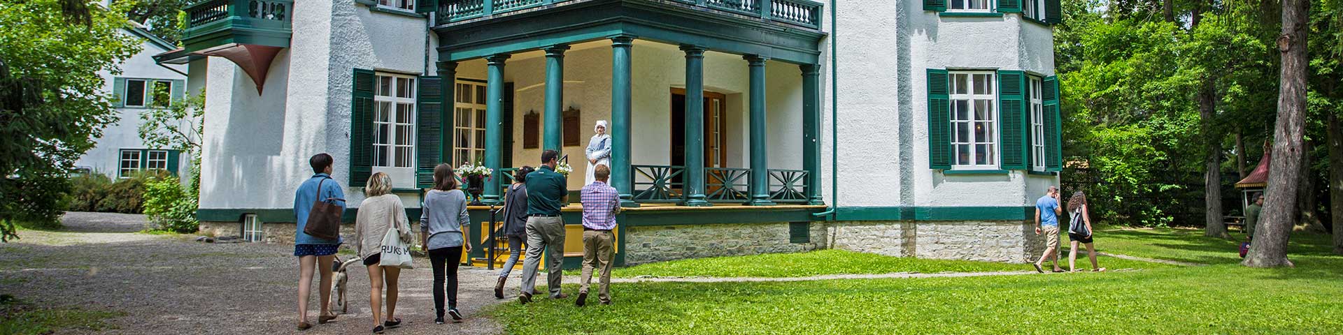 A group walks in front of the historic house.