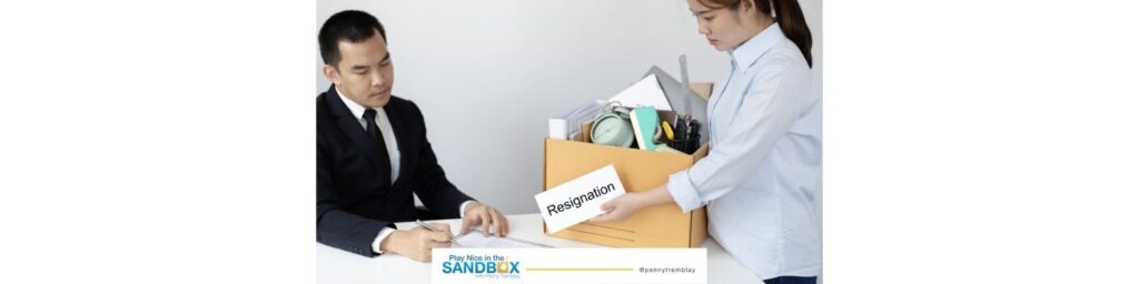 image of a woman with a box of belongings handing a letter labeled resignation to a man sitting at a desk due to lack of employee engagement