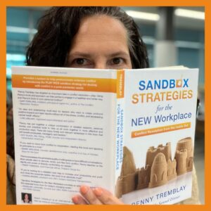 image of Penny Tremblay holding a copy of her new book Sandbox Strategies showing only her eyes and head behind the book