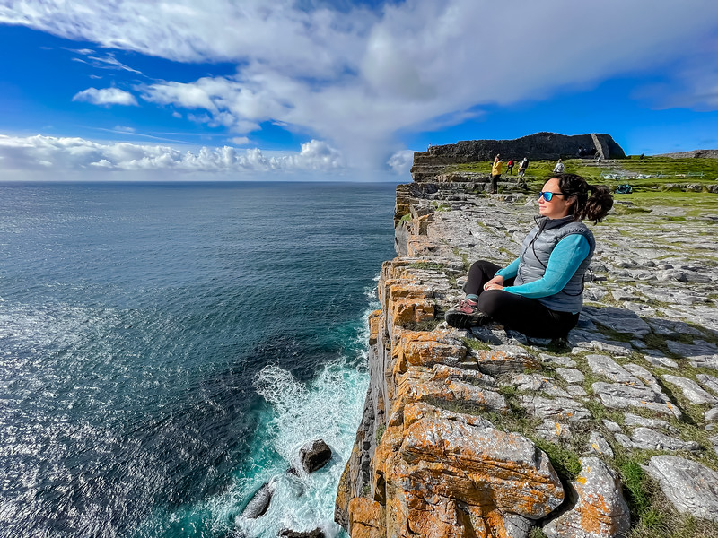 Lina Stock sentada en el borde del acantilado cerca de Dun Aengus en las Islas Aran