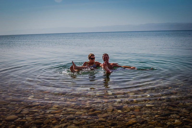 Lina and David Stock Jr (Americas Adventure Couple) of Divergent Travelers Adventure Travel Blog in soaking in the Dead Sea Jordan 