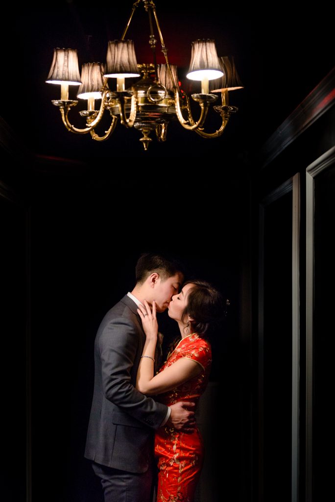 Bride and groom romantic kiss under light