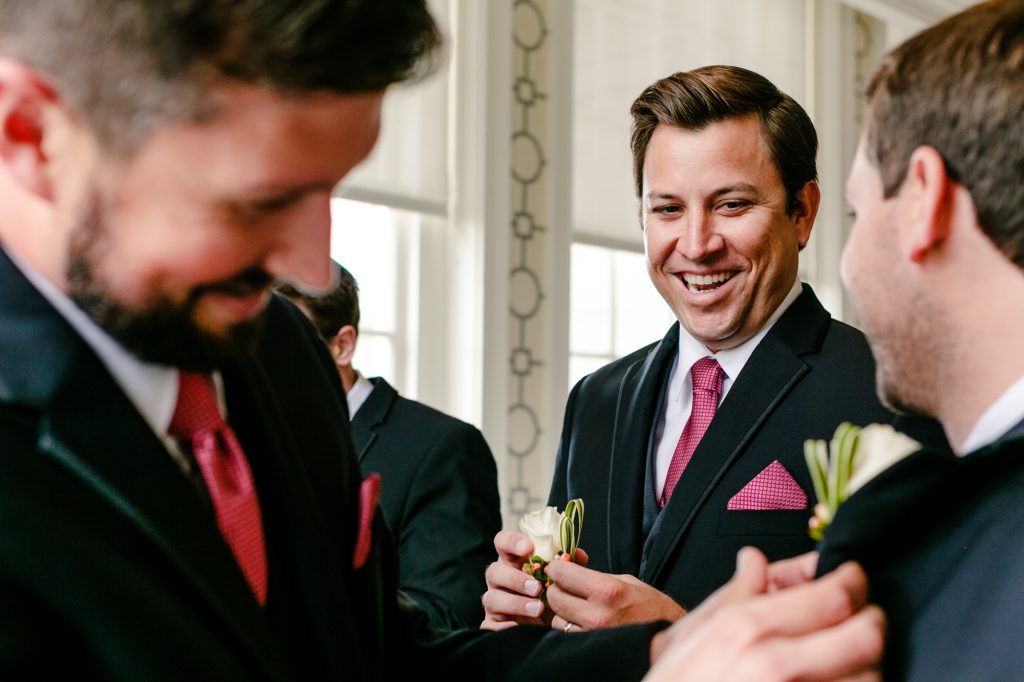 Groomsman laughing while holding white flower