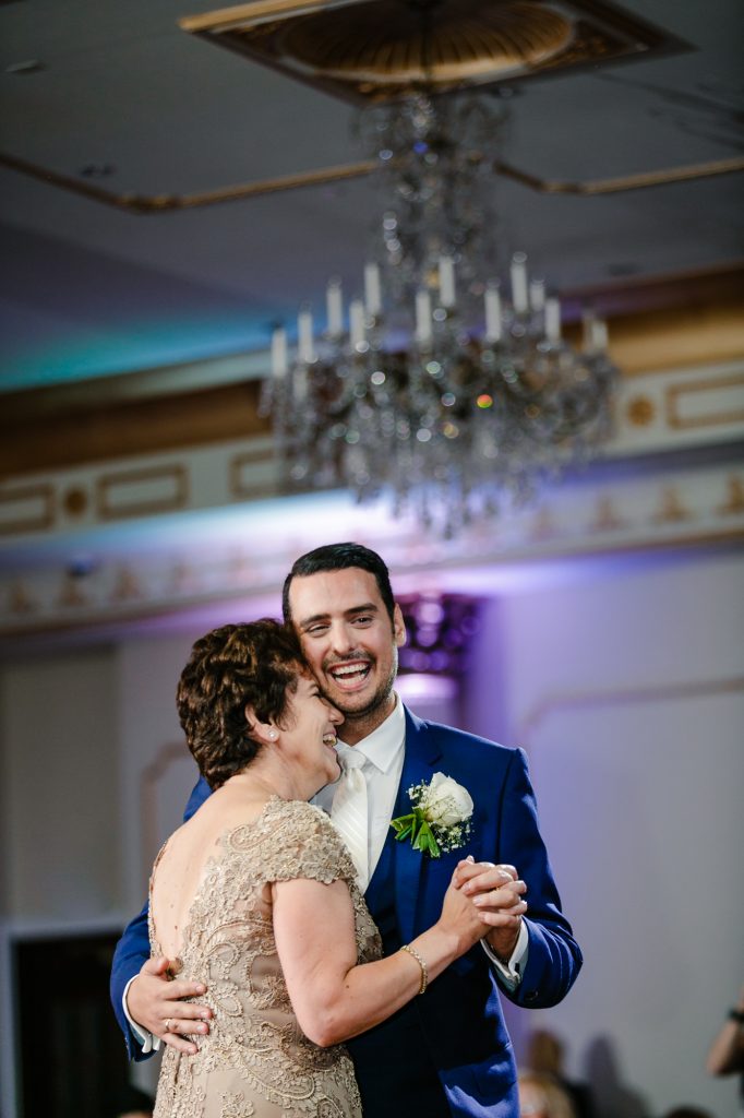 Groom smiling while dancing with mother