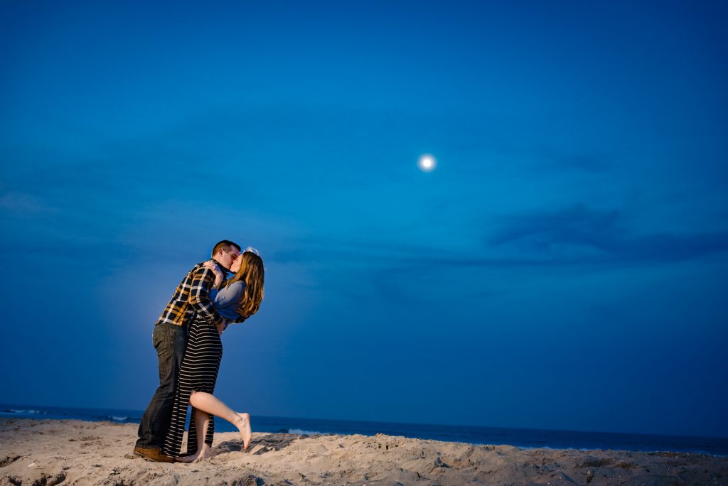 couple shares a kiss on the shore during their beach engagement shoot