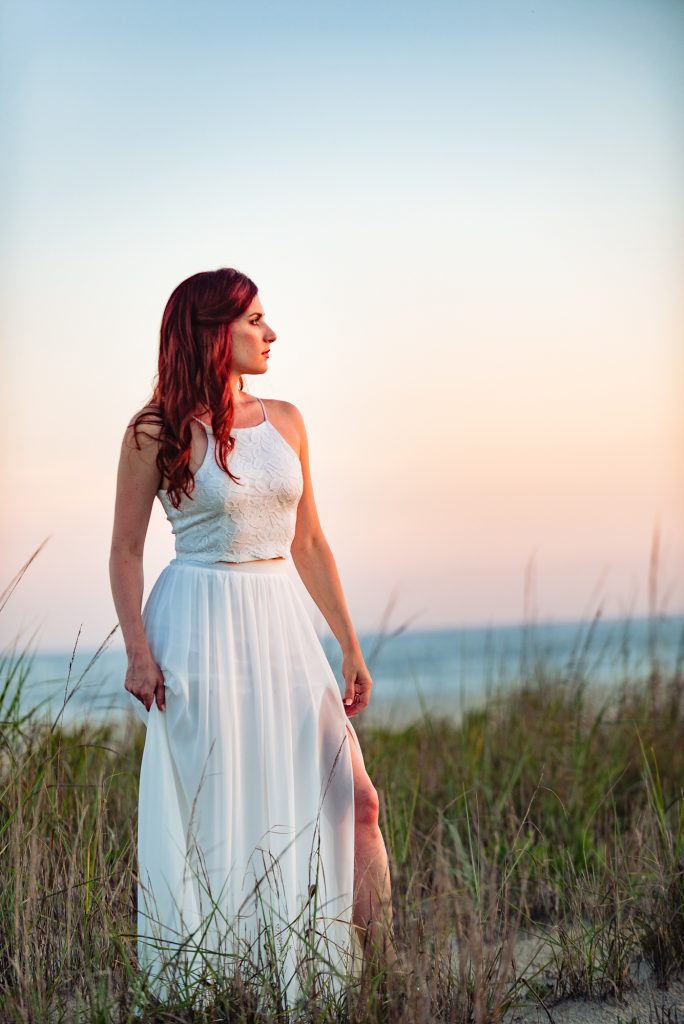 solo portrait of woman in white summer dress during her beach e-shoot