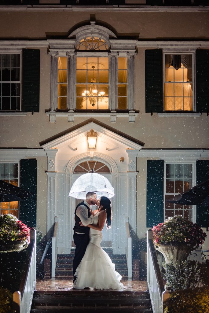 wedding day, bride and groom kissing under umbrella on rainy night