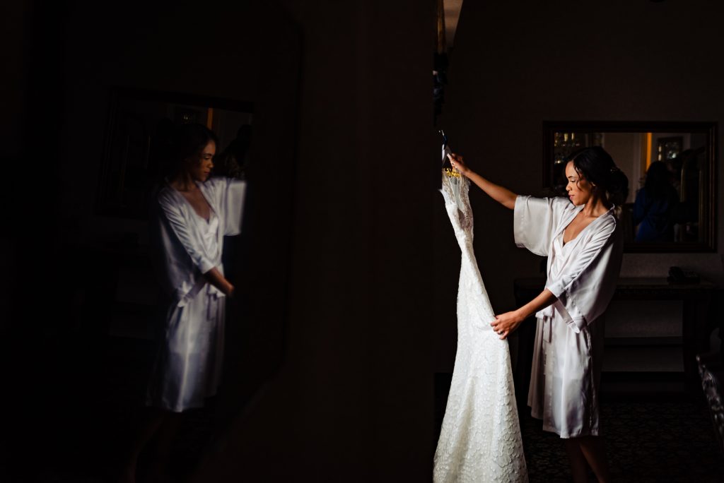 Reflection shot of bride preparing to put on her wedding dress