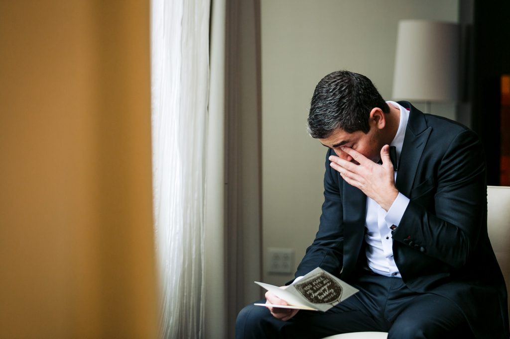 groom tearing up while reading the bride's letter for him