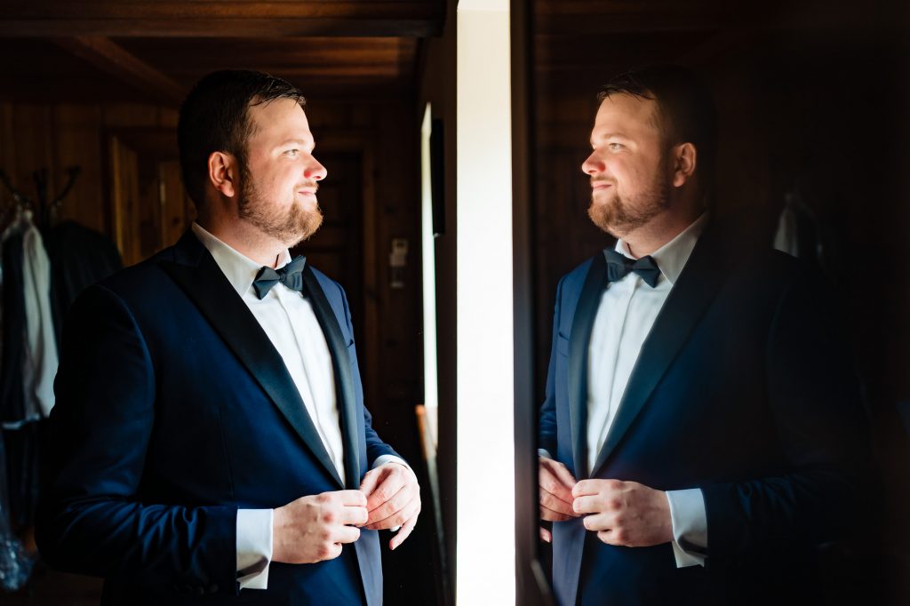 the groom smiling at his reflection on the mirror