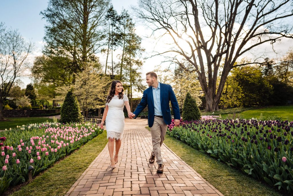 Longwood couple walking while holding hands during their Longwood Gardens Spring e-session