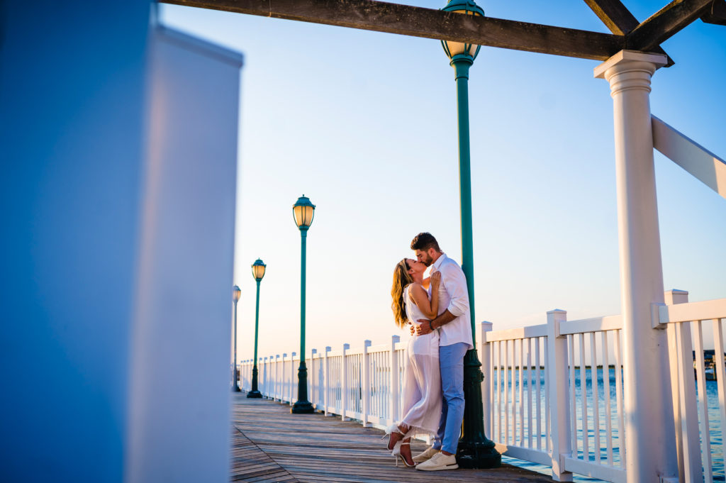 couple shares a kiss on the boardwalk during their beach engagement shoot at new jersey
