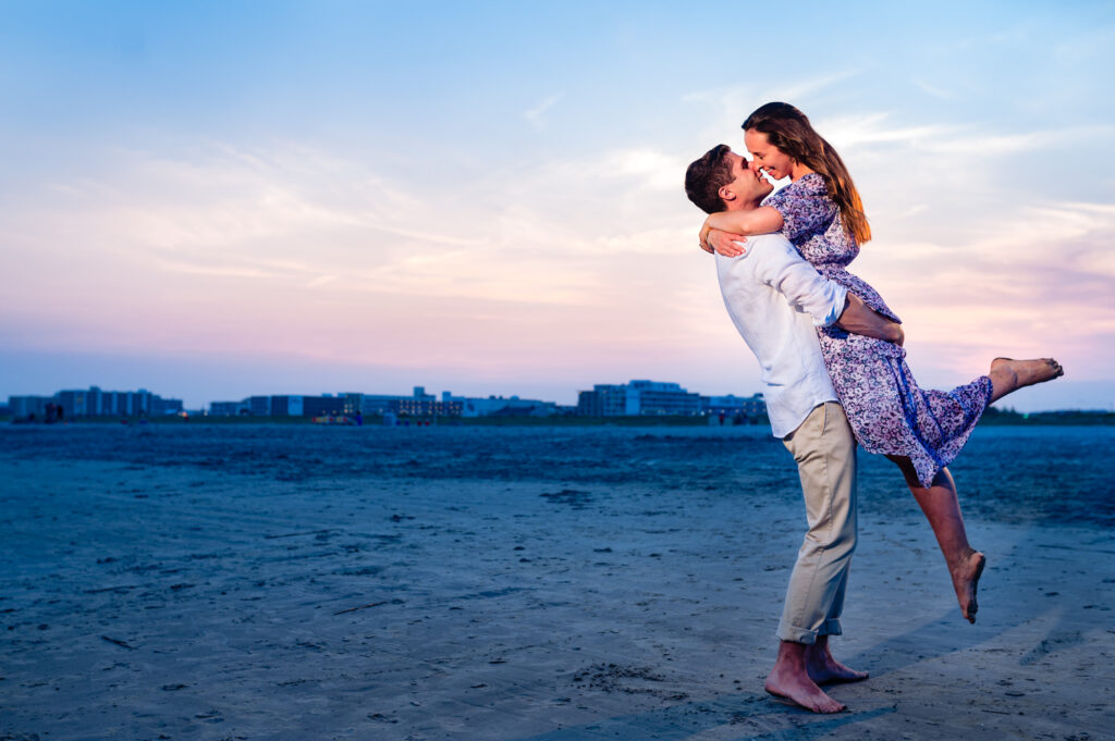 couple shares a kiss on the shores of cape may New Jersey during their beach engagement session